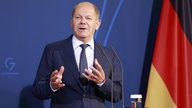 Bundeskanzler Olaf Scholz vor einer deutschen Flagge