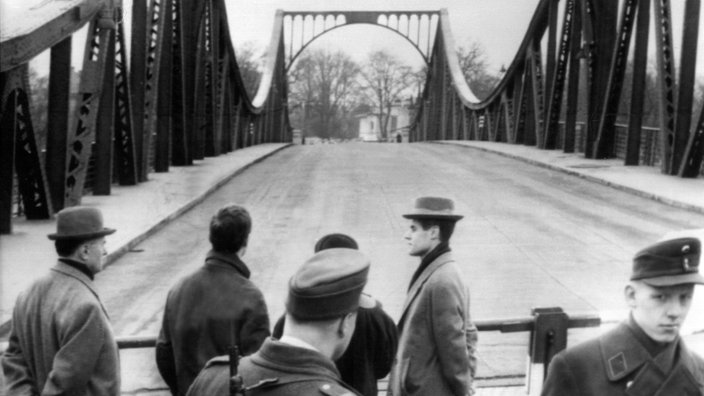 Brücke im Hintergrund, davor mehrere Menschen