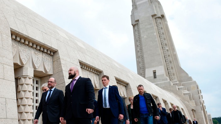 Eine Gruppe Menschen geht am Eingang des Beinhauses der Kriegs-Gedenkstätte Douaumont vorbei