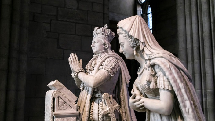 Marmorstatuen von Ludwig XVI. und Marie Antoinette in einer Kirche.