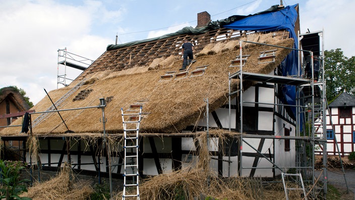 Ein Fachwerhaus wird mit Stroh gedeckt