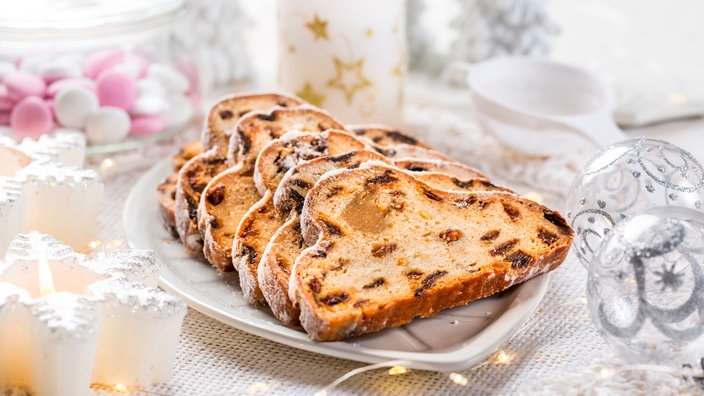 Eine Servierplatte mit aufgeschnittenem Christstollen, rundherum Weihnachtsdekoration