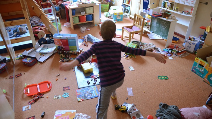 Kind in chaotischem Kinderzimmer.