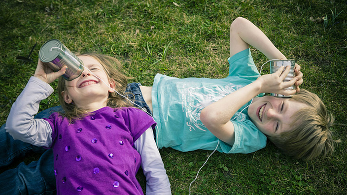 Kinder spielen mit Blechdosen