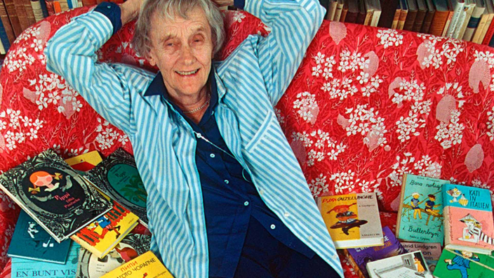 Astrid Lindgren auf einem Sofa, begraben unter Büchern.