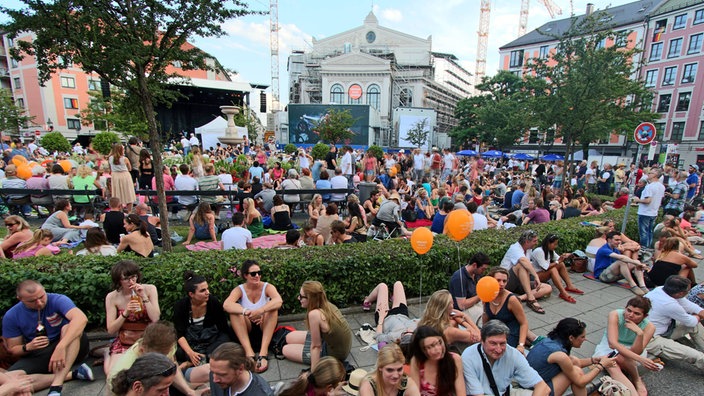 Zahlreiche Neschen sitzen am Gärtnerplatz in München