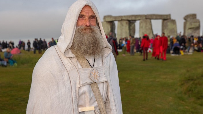 Ein heutiger Druide steht in weißer Kutte vor Stonehenge