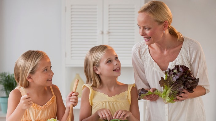 Mutter mit zwei eineiigen Zwillingstöchtern in einer Küche