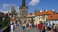 Das Bild zeigt eine belebte historische Brücke mit zwei Brückentürmen am Ende.