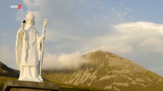 Statue von St. Patrick vor grünen Hügeln