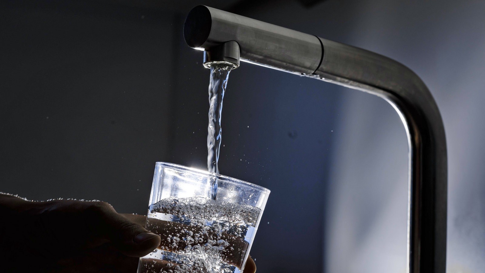 Wasser läuft aus einem Wasserhahn in ein Glas