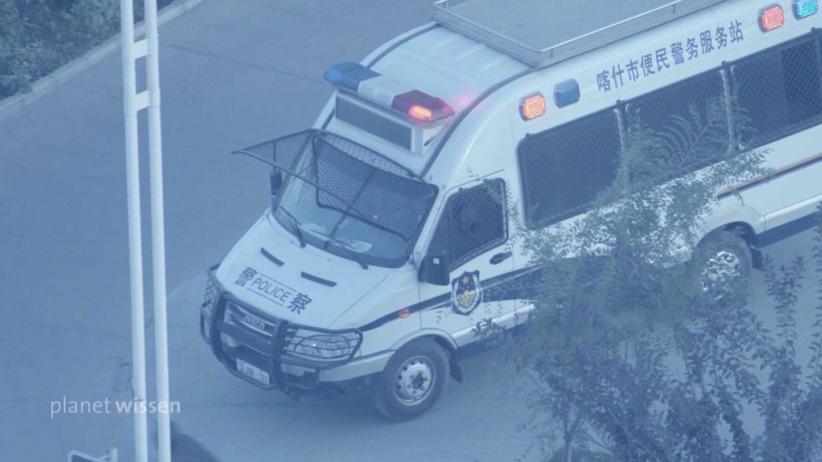 Blick von oben aus einem Fenster auf ein chinesisches Polizeiauto auf der Straße.