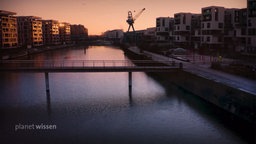 Eine weite Wasserfläche zwischen den Siedlungsgebäuden einer Stadt.