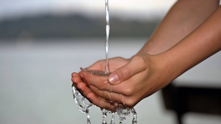 Wasserstrahl fließt in geöffnete Hände.