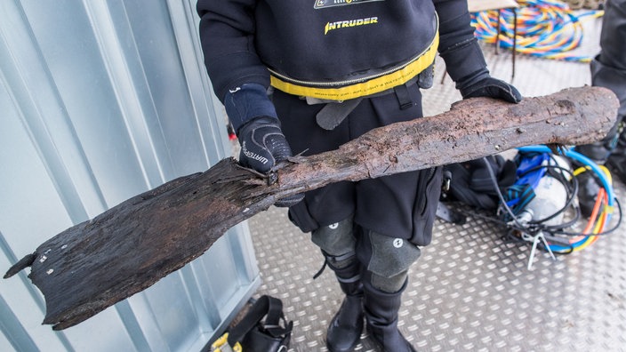 Mann hält eine Holzplanke in den Händen