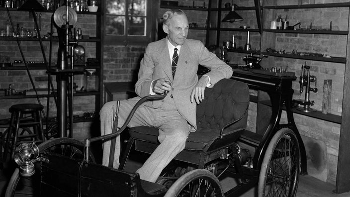 Henry Ford auf einem Modell seines ersten Autos